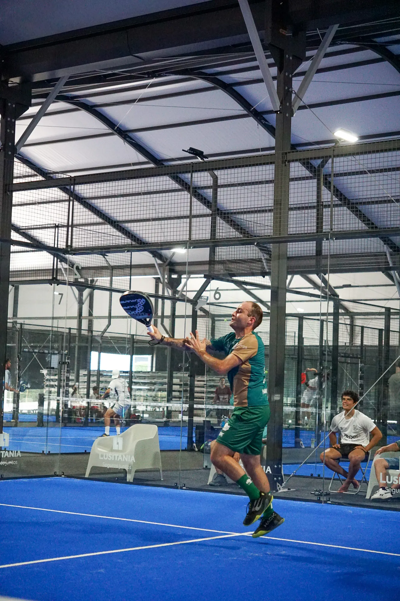 Jogador salta para um remate num pavilhão de padel coberto