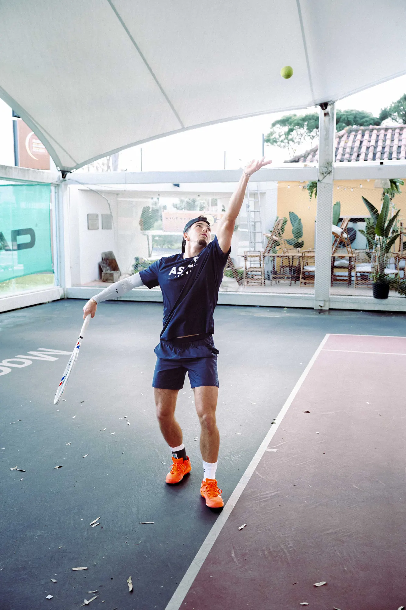 Jogador da Cunha e Silva Tennis Academy no momento do serviço, num campo coberto em Oeiras