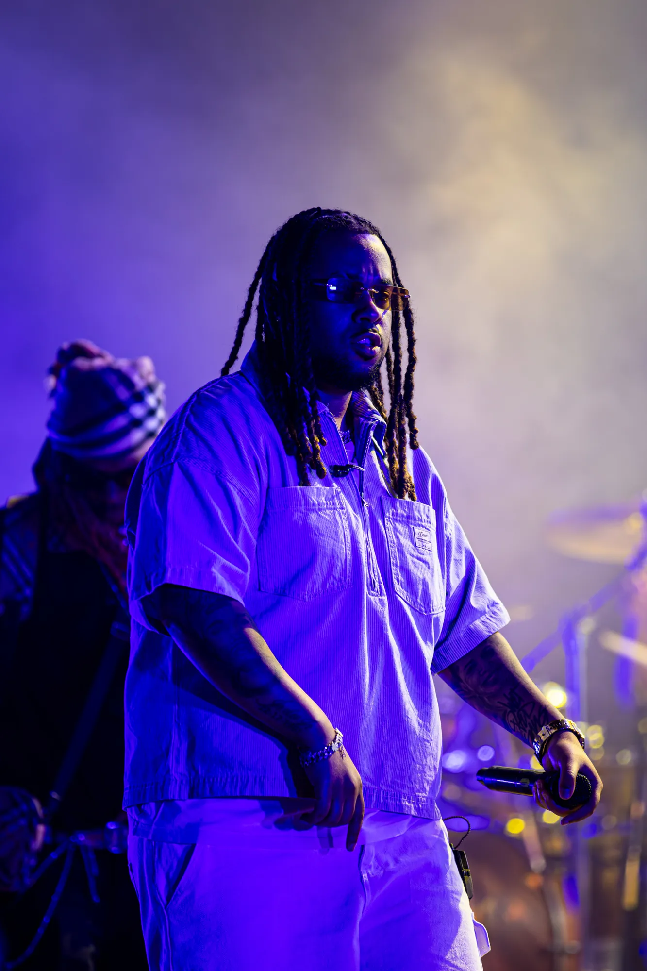 Artista de óculos escuros e camisa azul em palco no 231 Fest